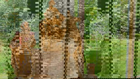 A set of three porcelain figurines on a white pedestal, with a large window and greenery in the background.