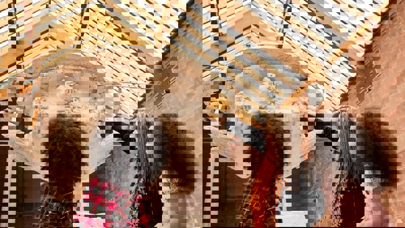 A person pointing to a large stone urn while two children look up at it in a museum.