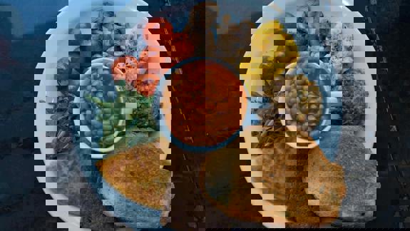 A plate of vegan full breakfast with beans, scrambled 'eggs,' tomatoes, mushrooms, and toast.