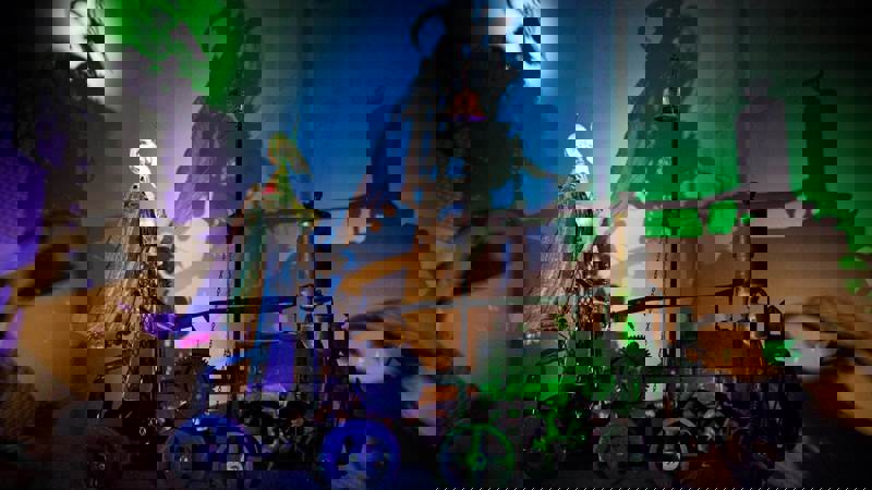 A kinetic sculpture from Sharmanka in Glasgow, with a strange figure on a wheeled machine casting dramatic shadows on a colourful wall.