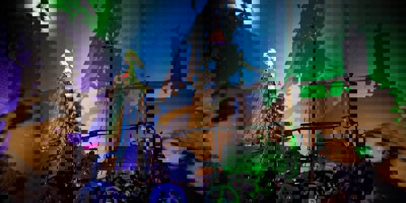 A kinetic sculpture from Sharmanka in Glasgow, with a strange figure on a wheeled machine casting dramatic shadows on a colourful wall.